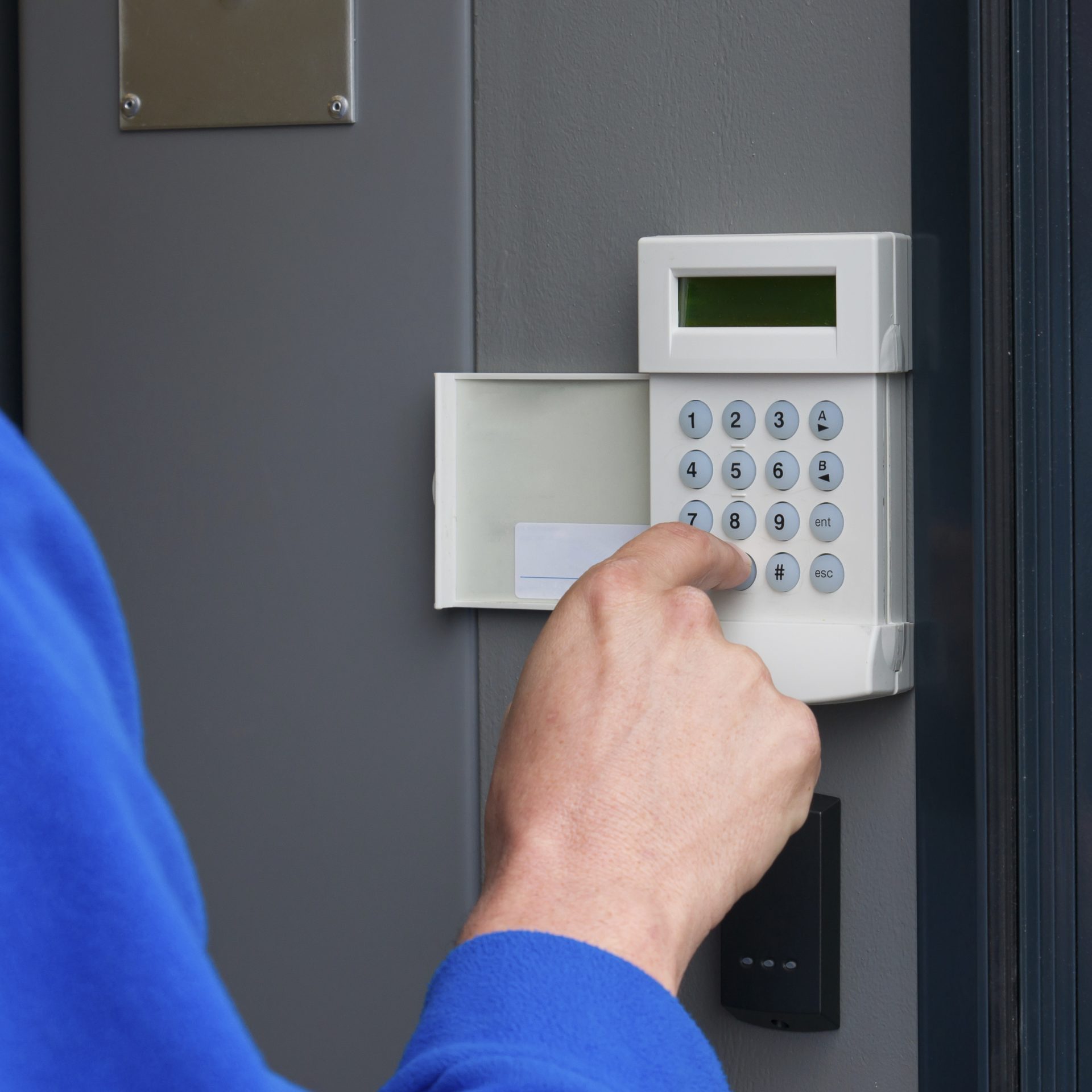 Person entering code to set the intruder alarm in a commerical building